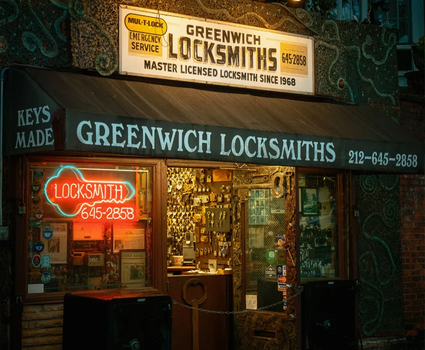 Außenansicht eines amerikanischen Schlüsseldienstes mit beleuchtetem Schaufenster, Neonreklame und einer großen Auswahl an Schlüsseln und Schlosszubehör